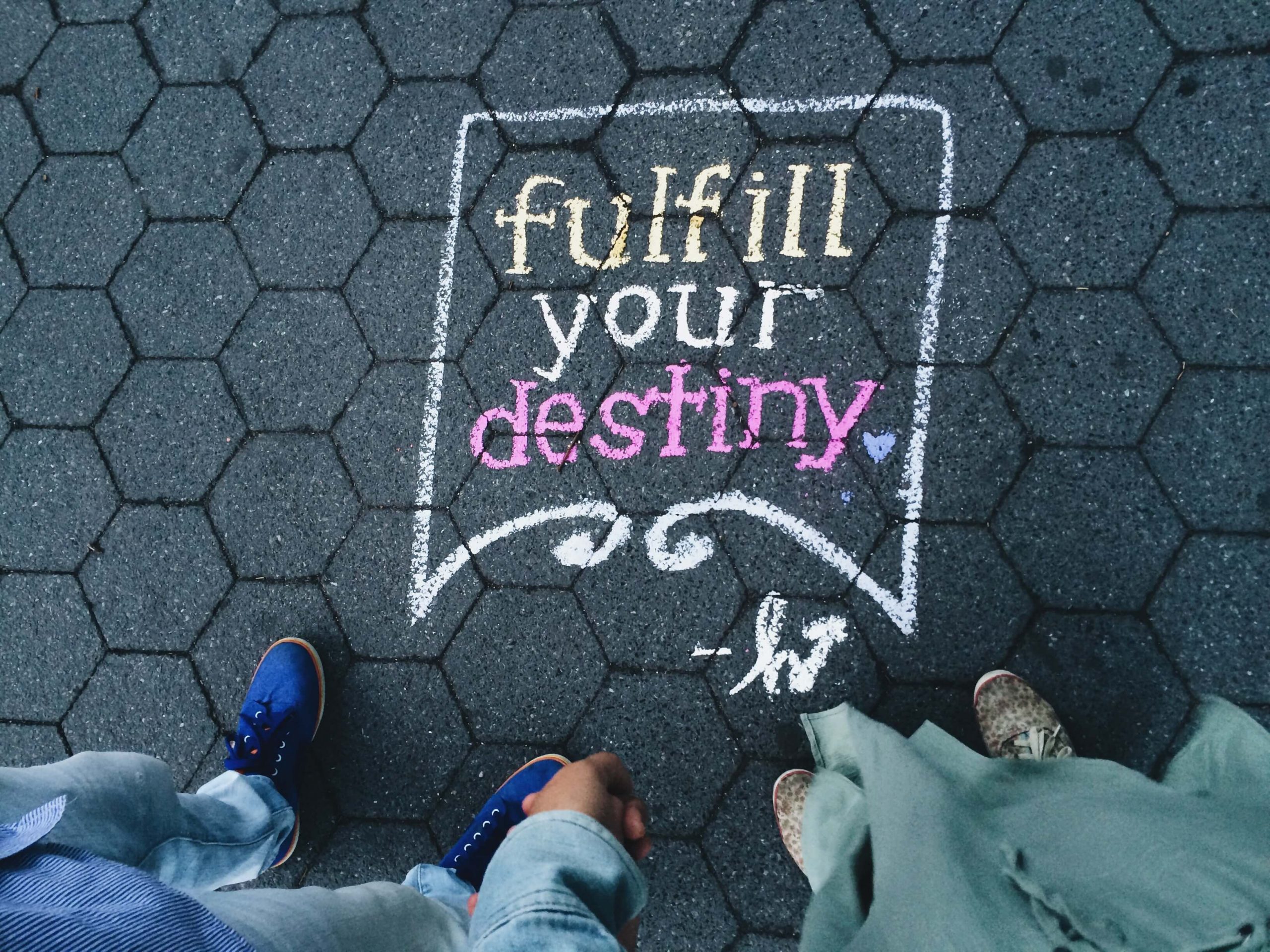 fulfill your destiny sign on the pavement with man and woman looking at it